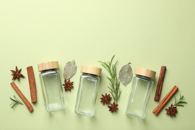 Photo of Different spices and glass jars on green background, flat lay