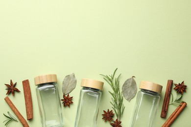 Photo of Different spices and glass jars on green background, flat lay. Space for text