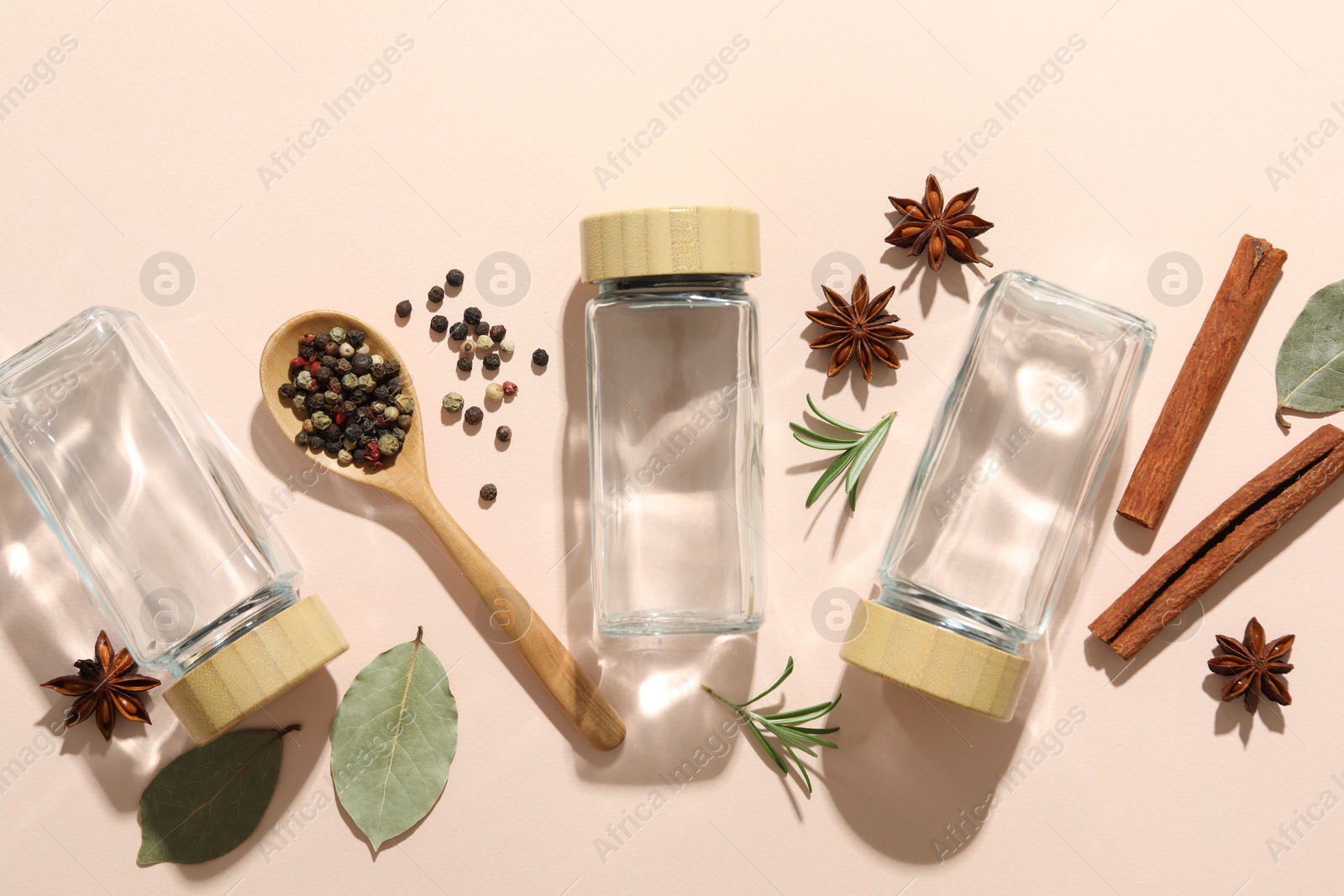 Photo of Different spices and glass jars on beige background, flat lay