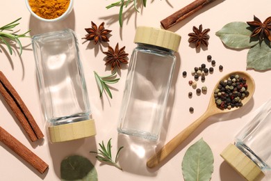 Different spices and glass jars on beige background, flat lay