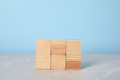 Wooden cubes on table against light blue background