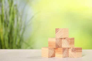 Photo of Wooden cubes on light table against blurred background. Space for text