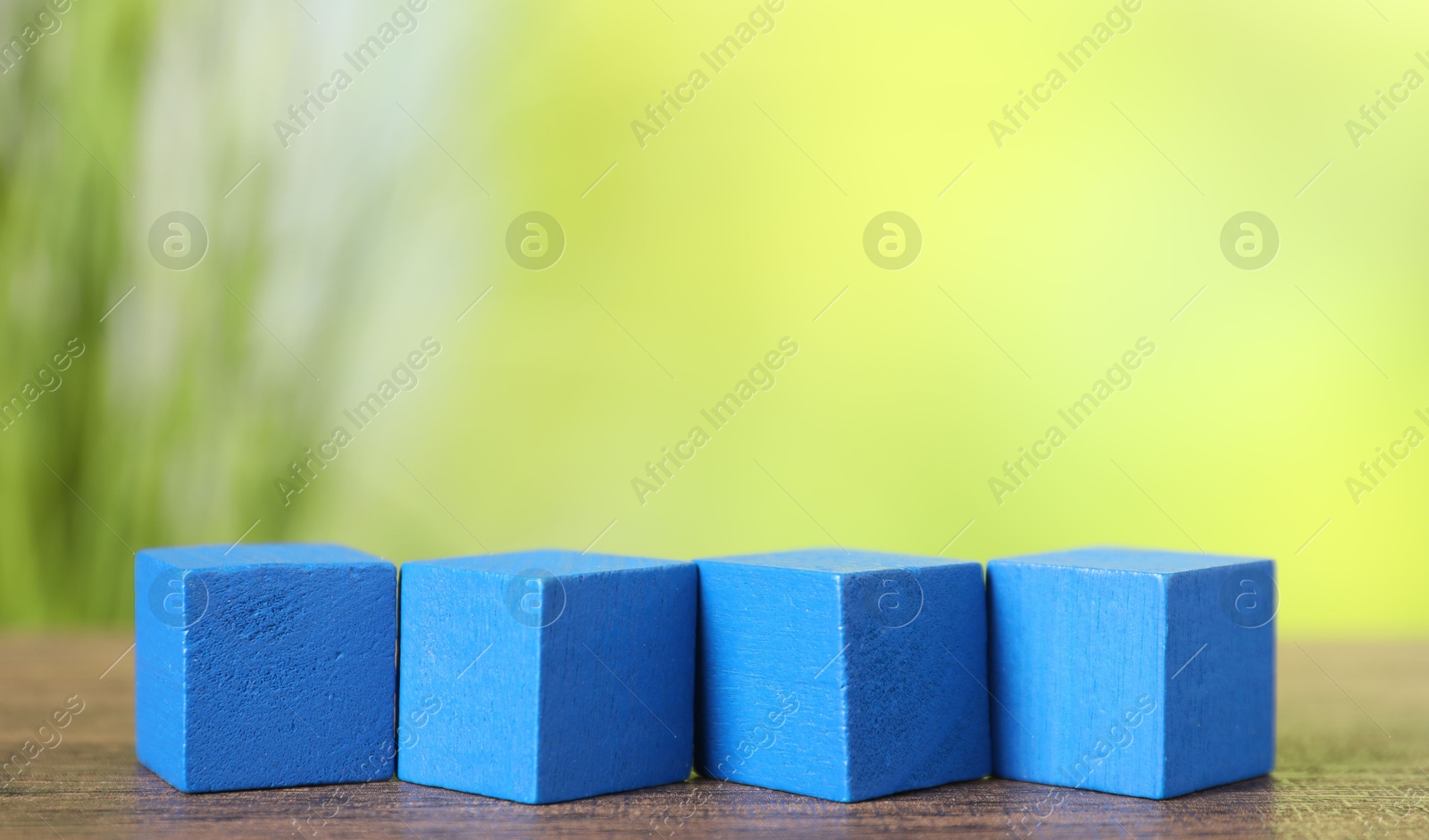 Photo of Blue cubes on wooden table against blurred background. Space for text