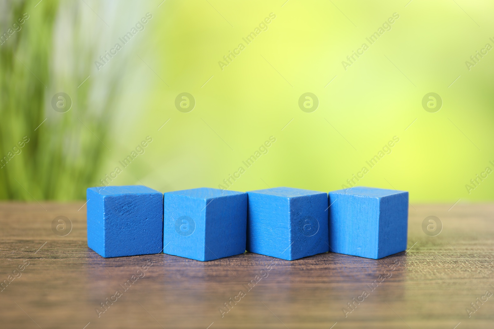 Photo of Blue cubes on wooden table against blurred background. Space for text