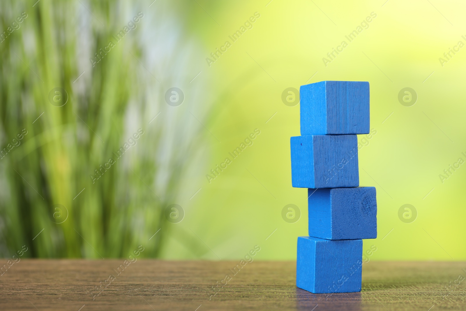 Photo of Stack of blue cubes on wooden table against blurred background. Space for text