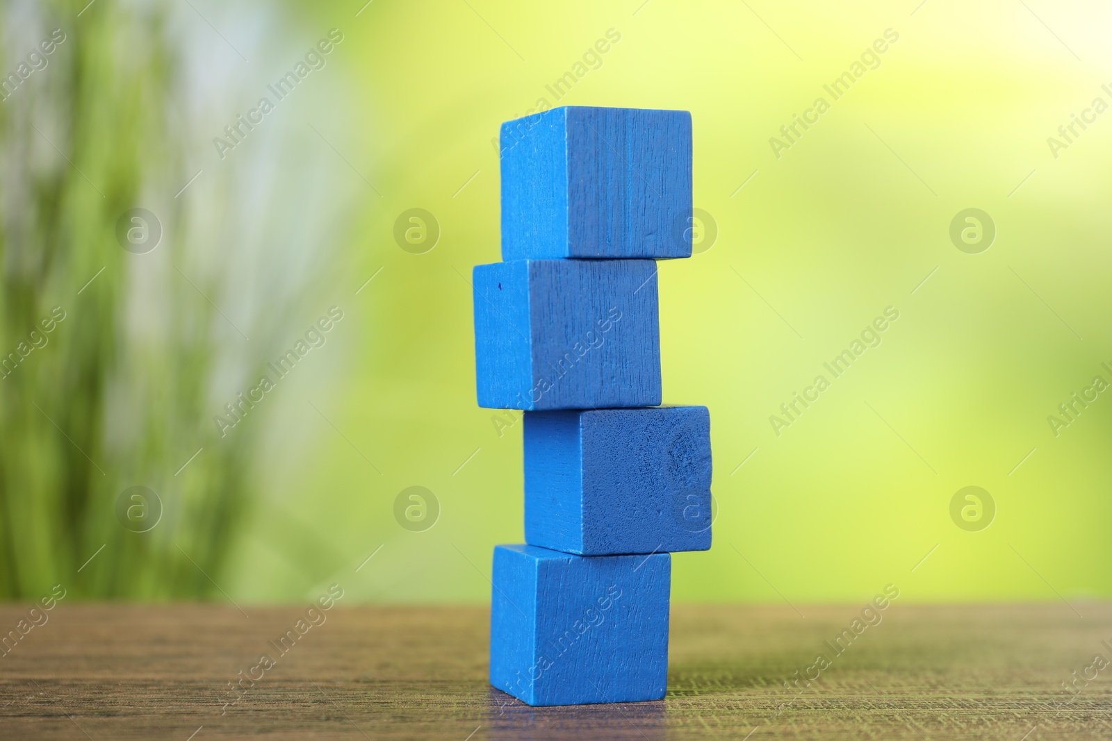 Photo of Stack of blue cubes on wooden table against blurred background