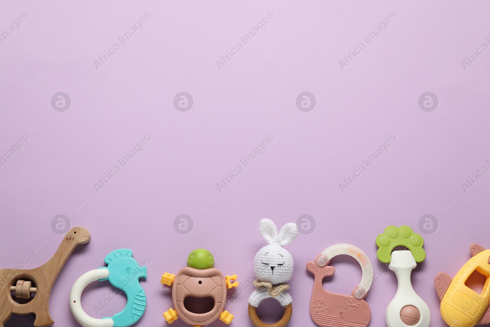 Photo of Different baby rattles on lilac background, flat lay. Space for text