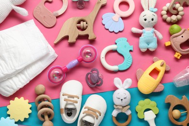 Photo of Different baby rattles, diapers and booties on color background, flat lay