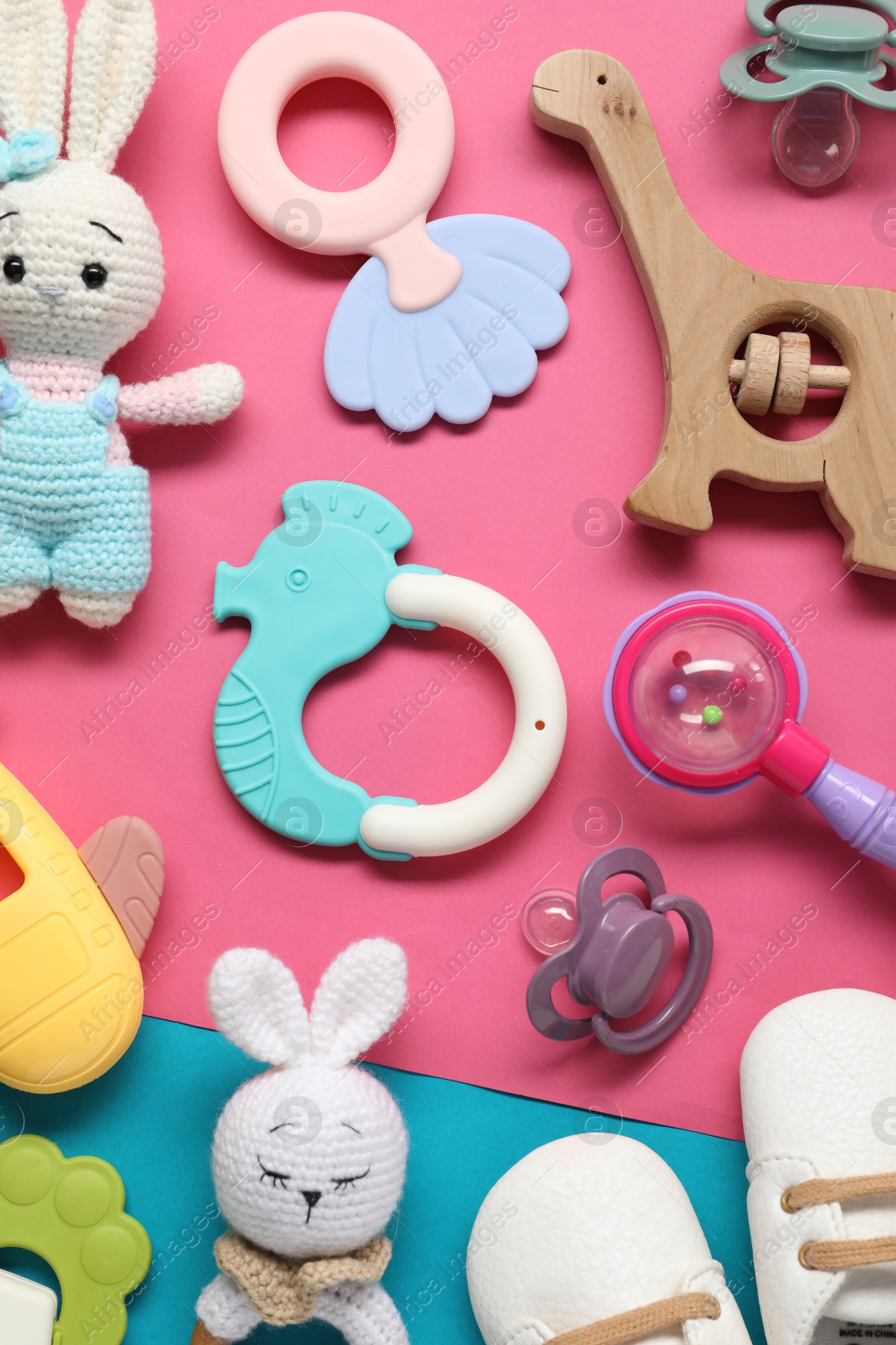 Photo of Different baby rattles and booties on color background, flat lay