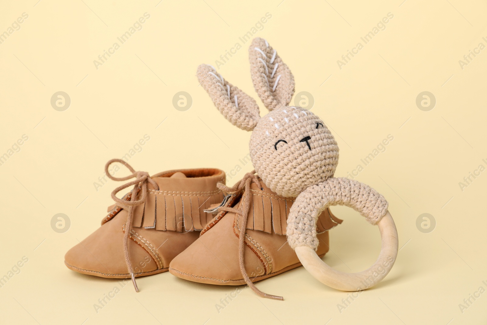 Photo of Baby rattle and booties on beige background