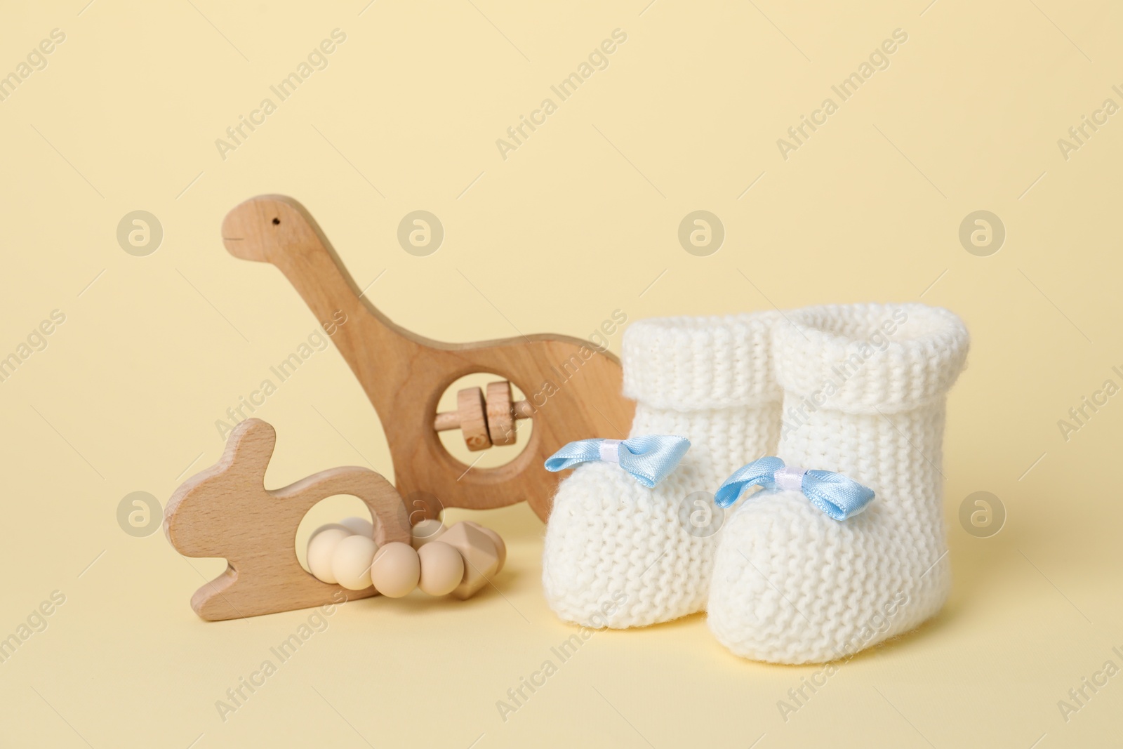 Photo of Baby rattles and booties on beige background