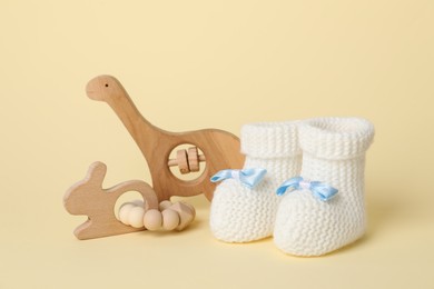 Photo of Baby rattles and booties on beige background