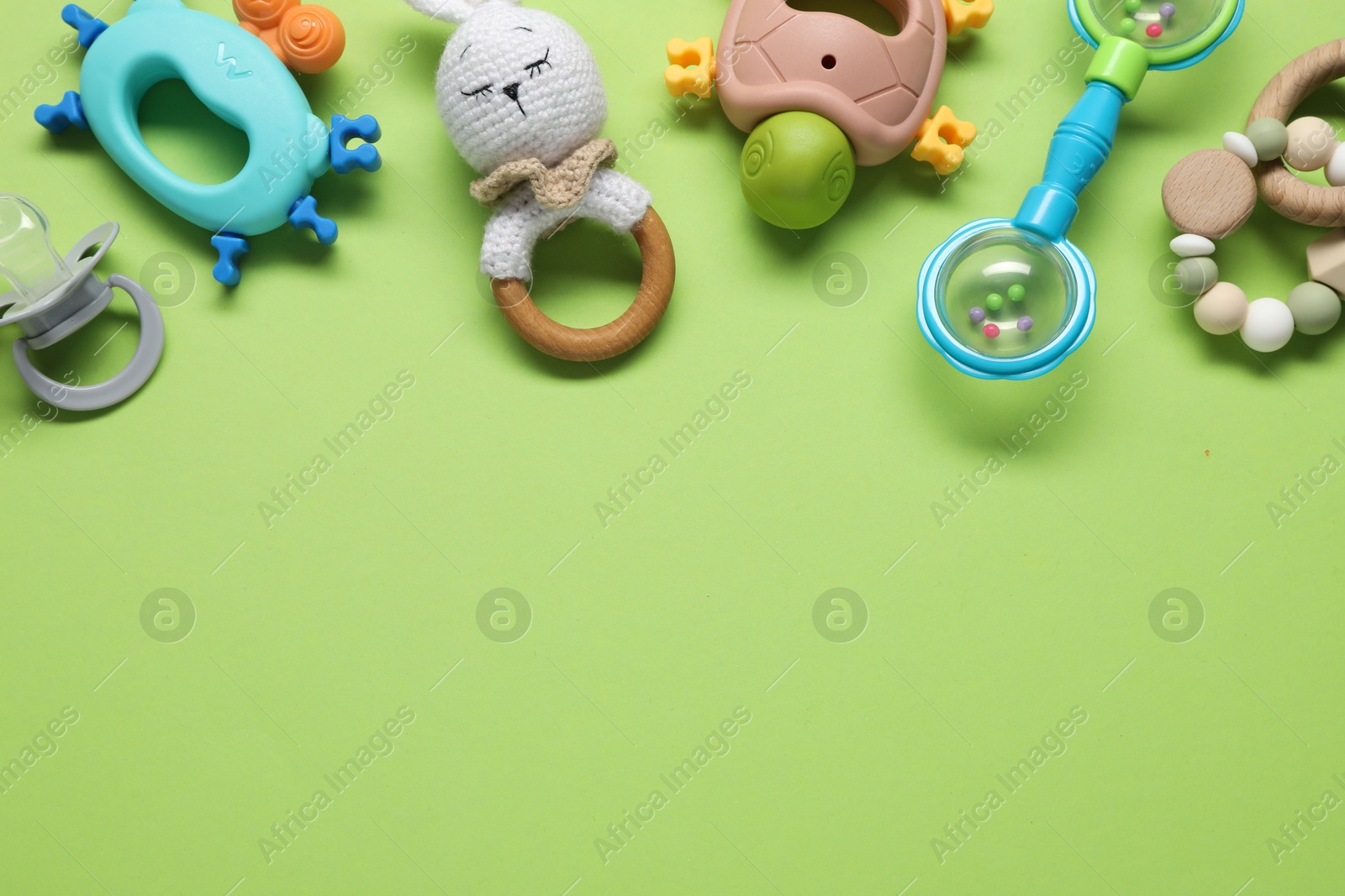 Photo of Different baby rattles on green background, flat lay. Space for text