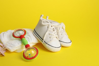 Baby rattle and accessories on yellow background