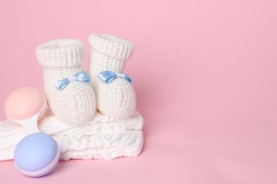 Baby rattle, booties and diapers on pink background. Space for text