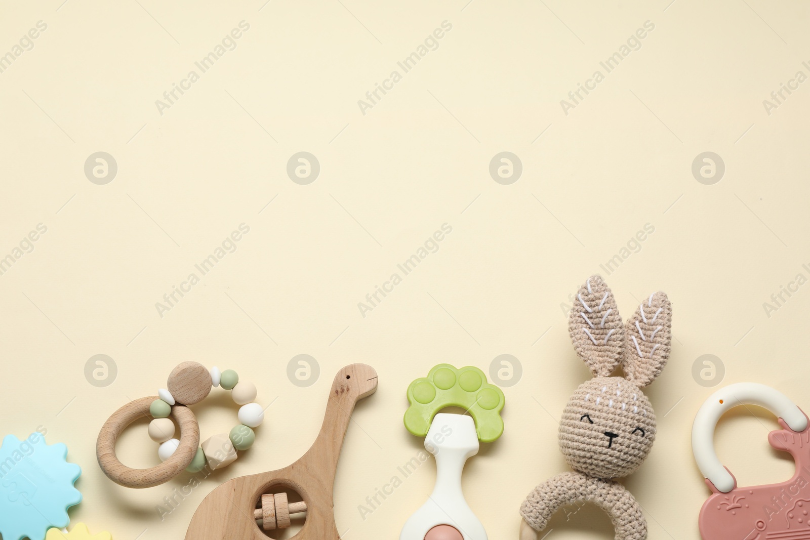 Photo of Different baby rattles on beige background, flat lay. Space for text