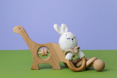 Photo of Different baby rattles on green table against blue background