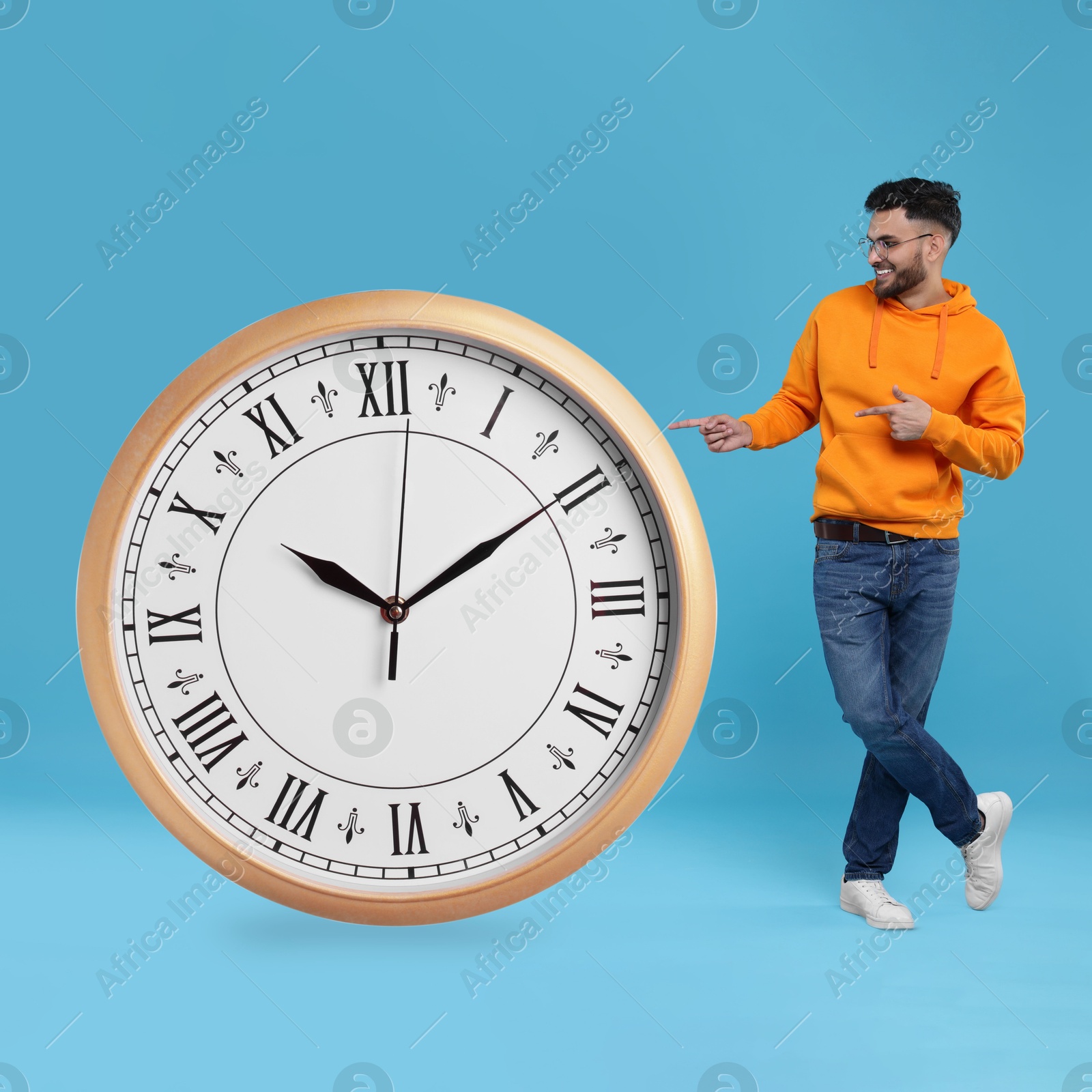 Image of Man pointing at big clock on light blue background