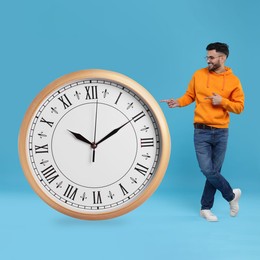 Man pointing at big clock on light blue background