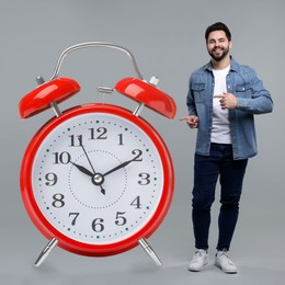 Image of Man pointing at big alarm clock on grey background