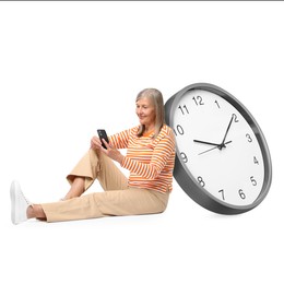 Image of Mature woman with smartphone and big clock on white background