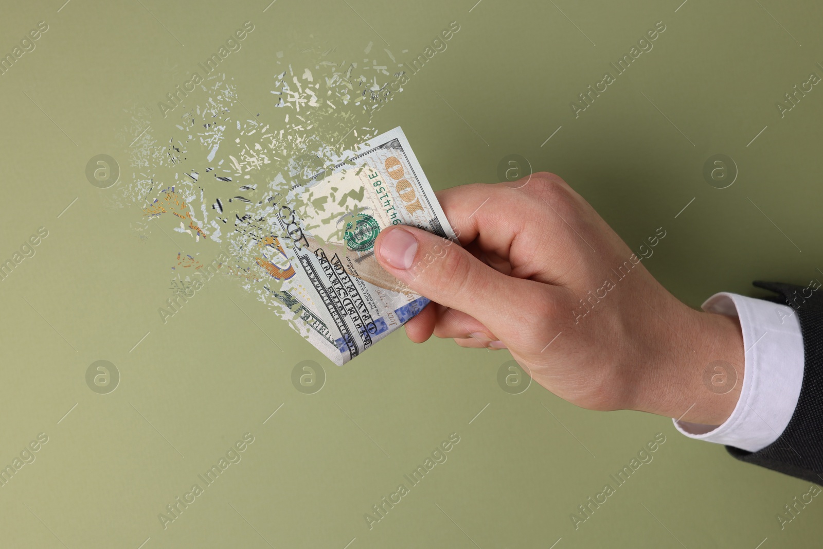 Image of Man holding dissolving dollar banknotes on olive background. Financial crisis