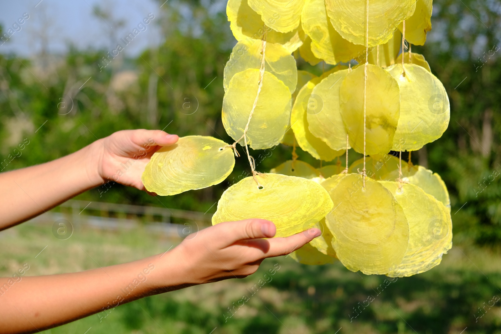 Photo of Woman enjoying beautiful wind chimes outdoors, closeup