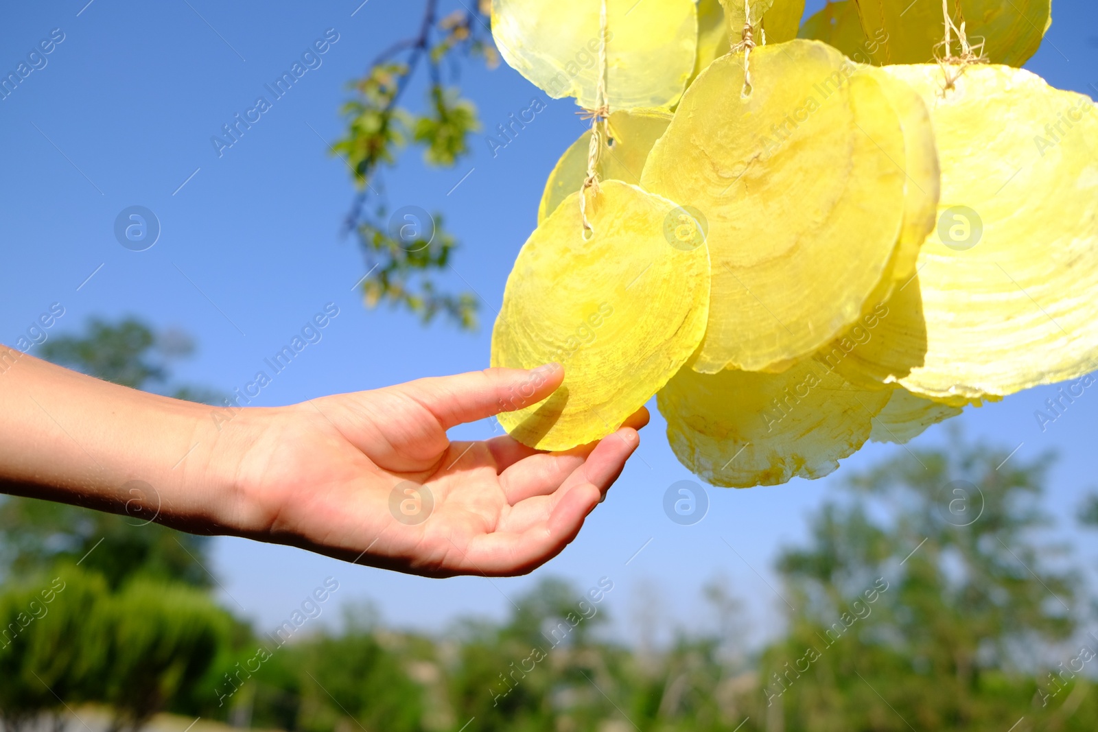 Photo of Woman enjoying beautiful wind chimes outdoors, closeup