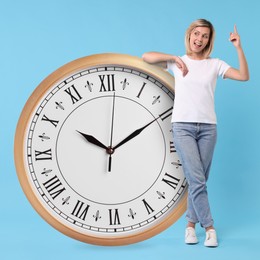 Image of Woman and big clock on light blue background