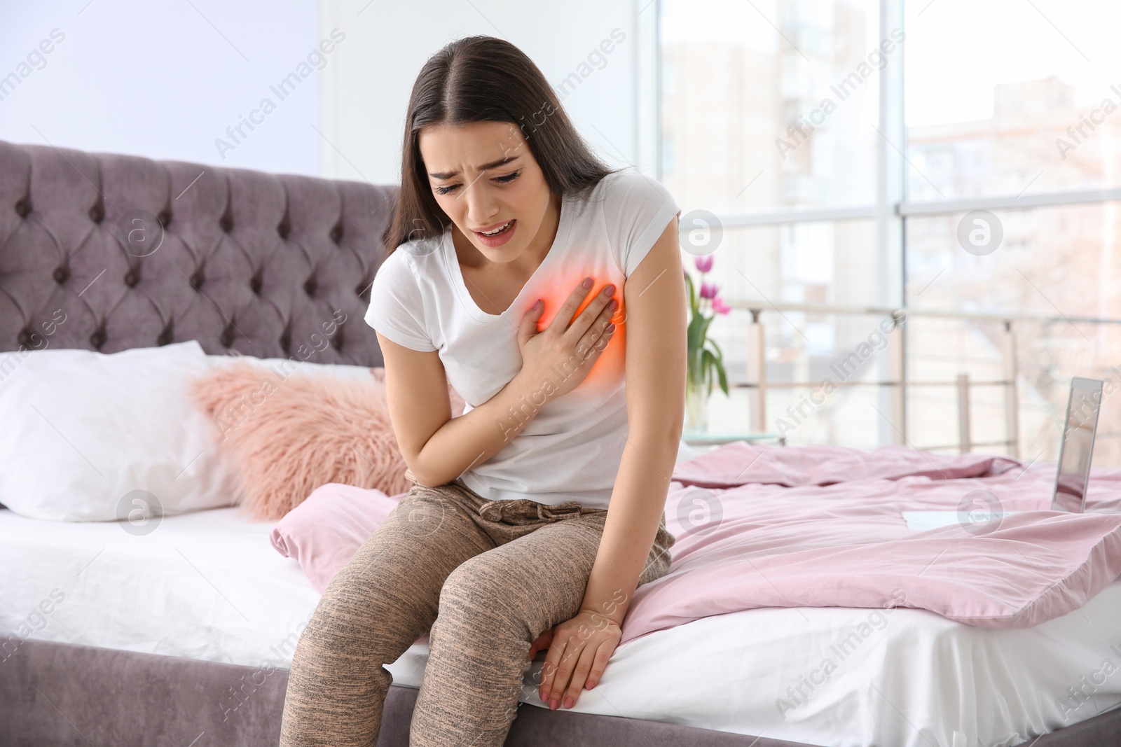 Image of Young woman suffering from pain in chest at home. Heart disease