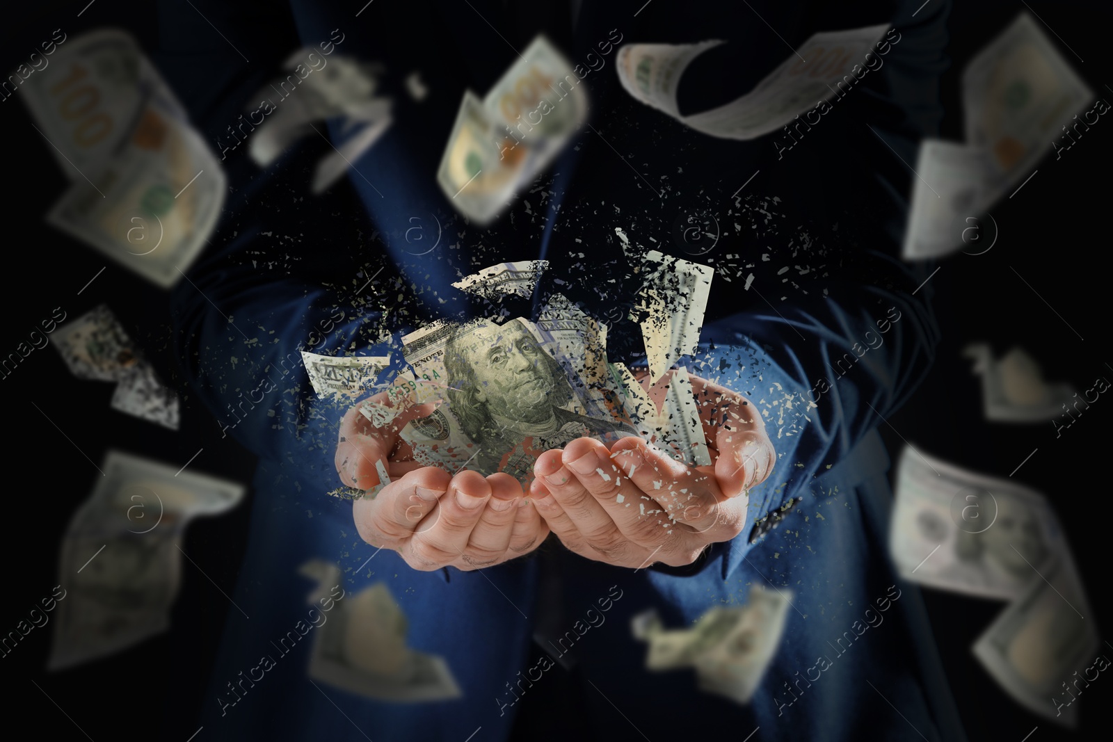 Image of Businessman holding dissolving dollar banknotes in darkness, closeup. Money falling around. Financial crisis