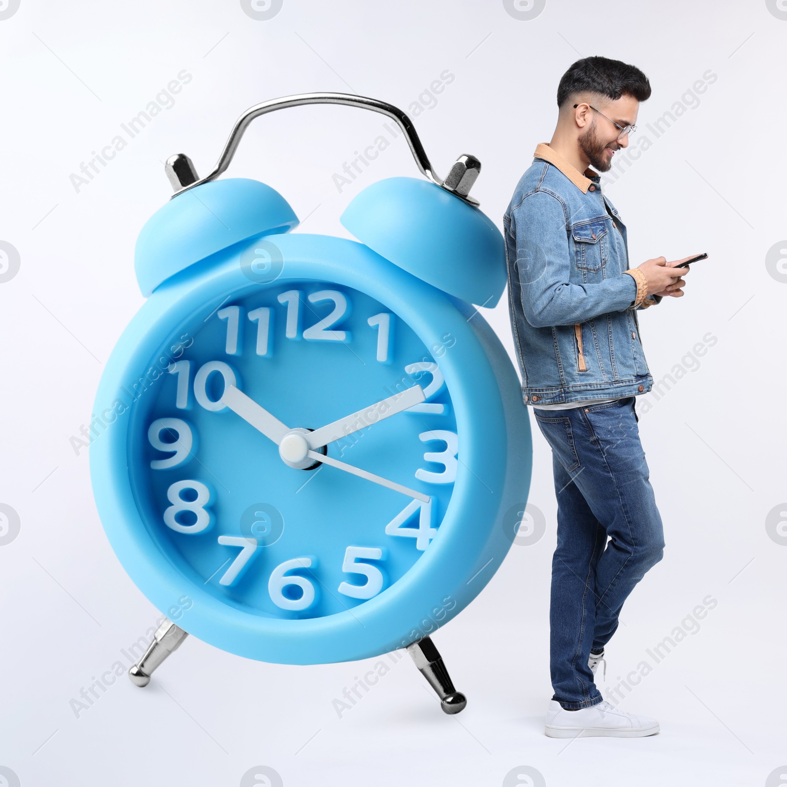 Image of Man with smartphone and big alarm clock on white background