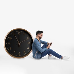 Man with smartphone and big clock on white background