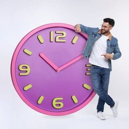 Image of Man pointing at big clock on white background