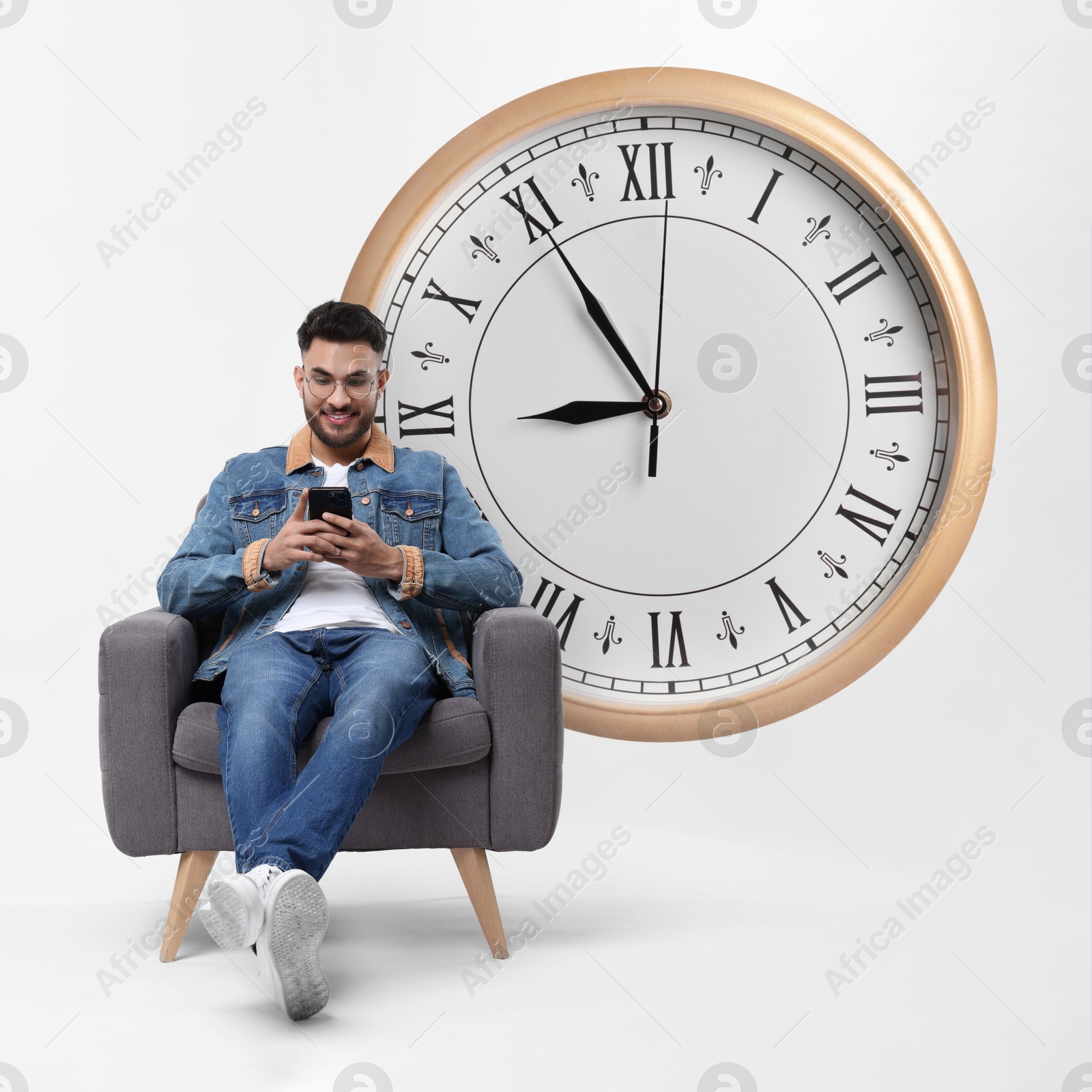 Image of Man with smartphone sitting in armchair near big clock on white background