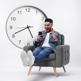 Image of Happy man with smartphone sitting in armchair near big clock on white background