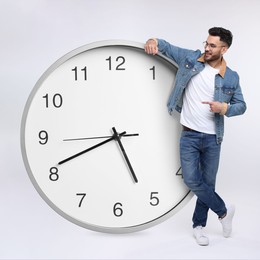 Man pointing at big clock on white background