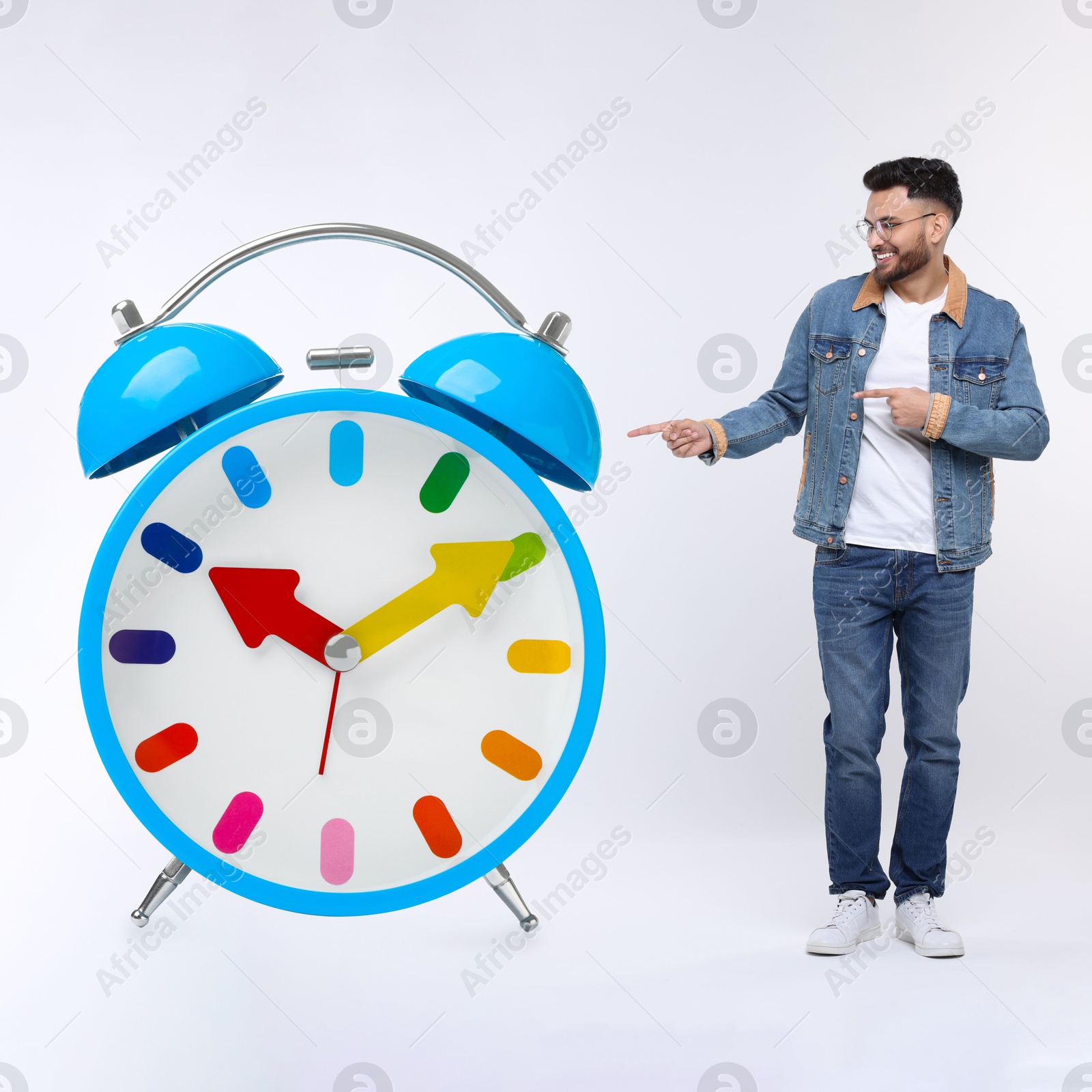 Image of Man pointing at big alarm clock on white background