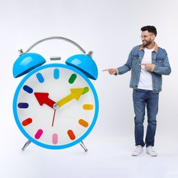 Image of Man pointing at big alarm clock on white background