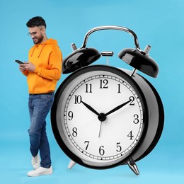 Man with smartphone and big alarm clock on light blue background