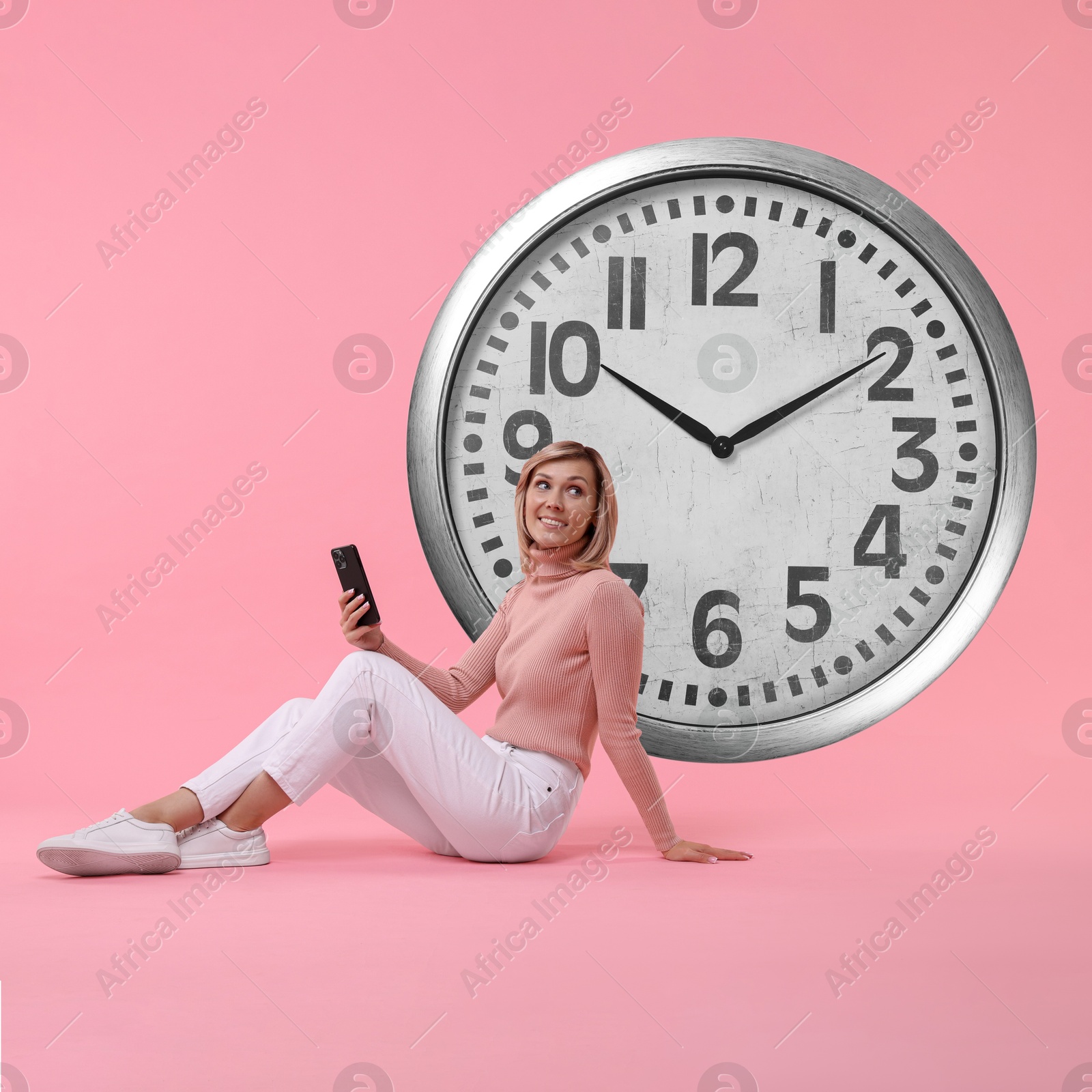 Image of Woman with smartphone and big clock on pink background