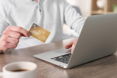 Photo of Online banking. Man with credit card and laptop paying purchase at table, closeup