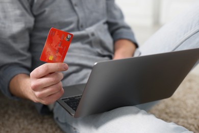 Photo of Online banking. Man with credit card and laptop paying purchase at home, closeup