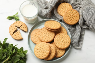 Tasty sandwich cookies, glass of milk and mint on white table, above view