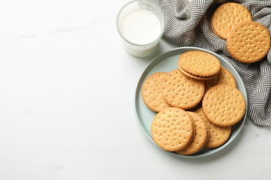 Tasty sandwich cookies and glass of milk on white table, above view. Space for text