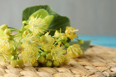 Photo of Fresh linden leaves and flowers on wicker mat, closeup