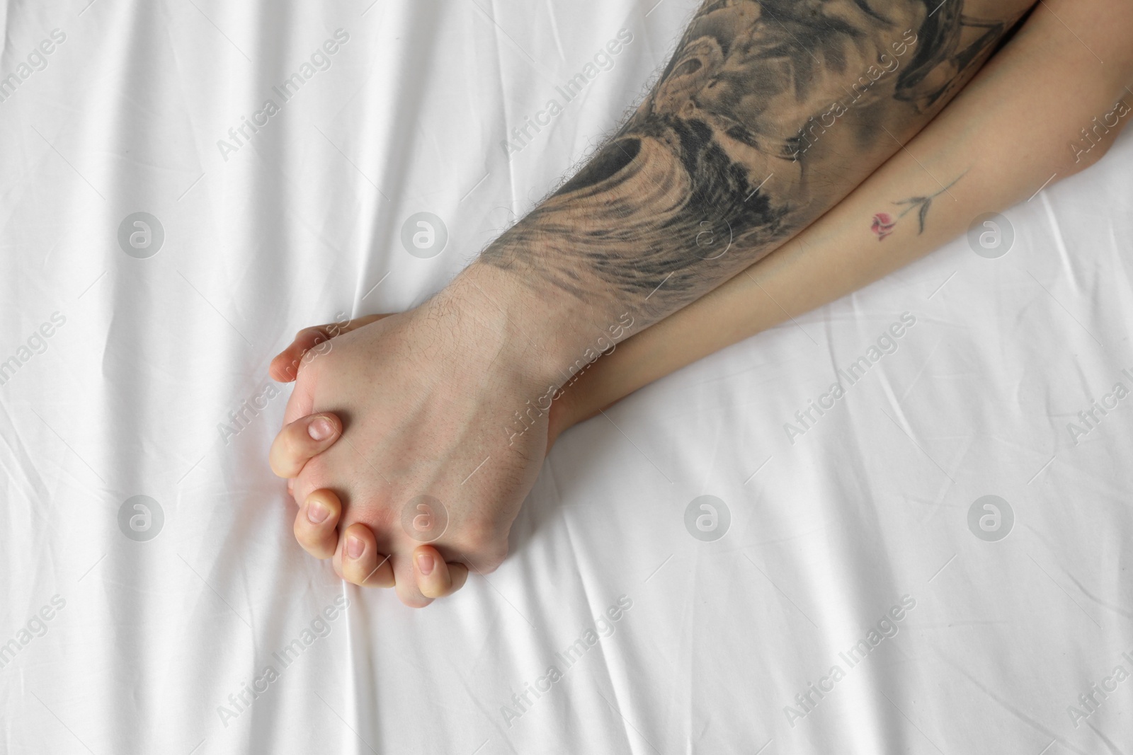 Photo of Lovely couple holding hands in bed, top view