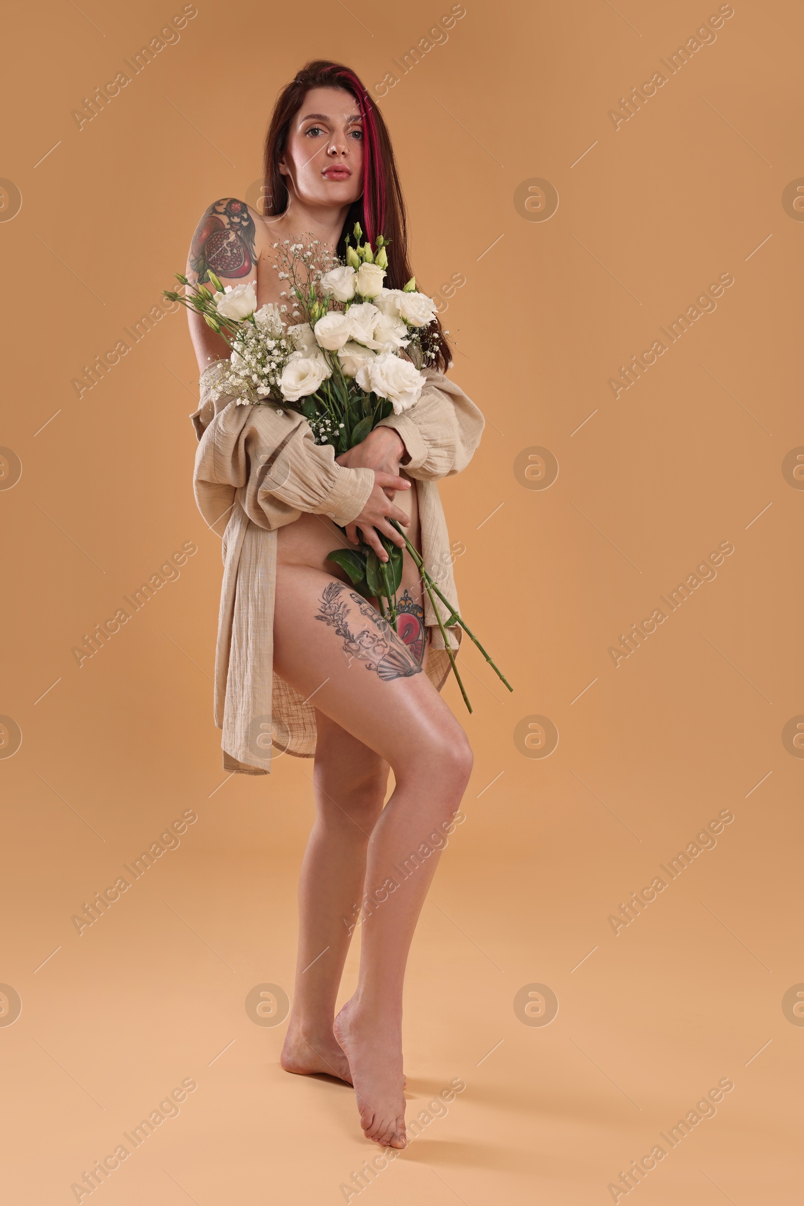 Photo of Sexy nude woman with bouquet of flowers and shirt on beige background