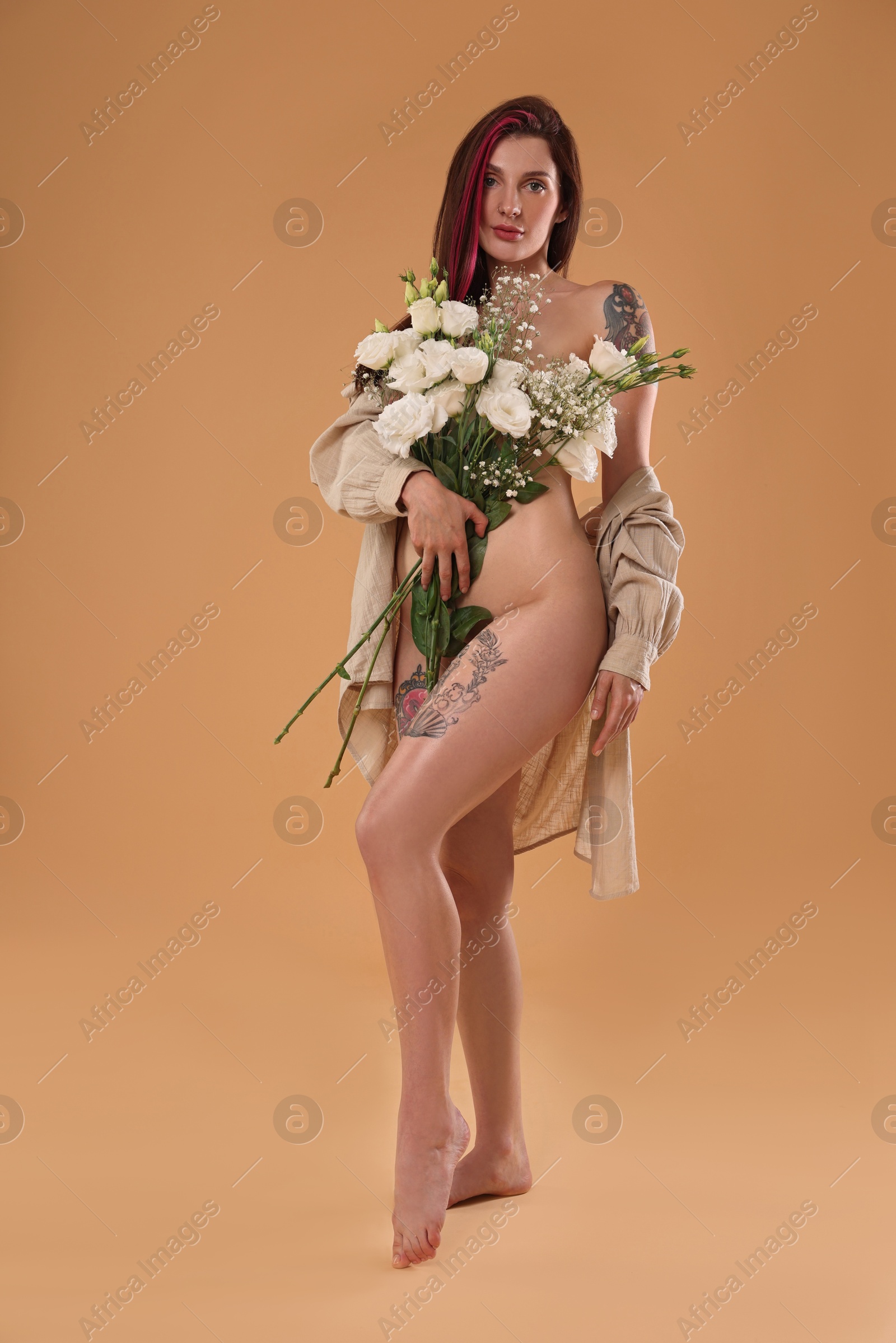 Photo of Sexy nude woman with bouquet of flowers and shirt on beige background