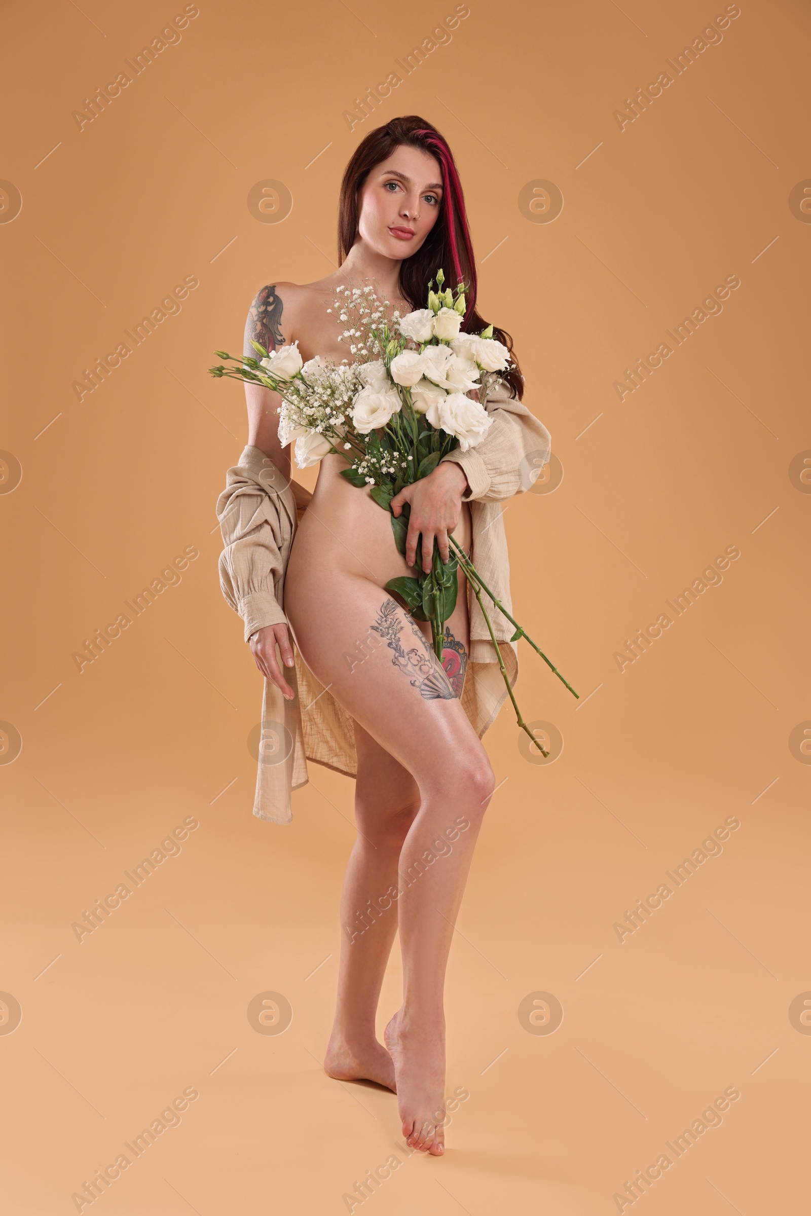 Photo of Sexy nude woman with bouquet of flowers and shirt on beige background